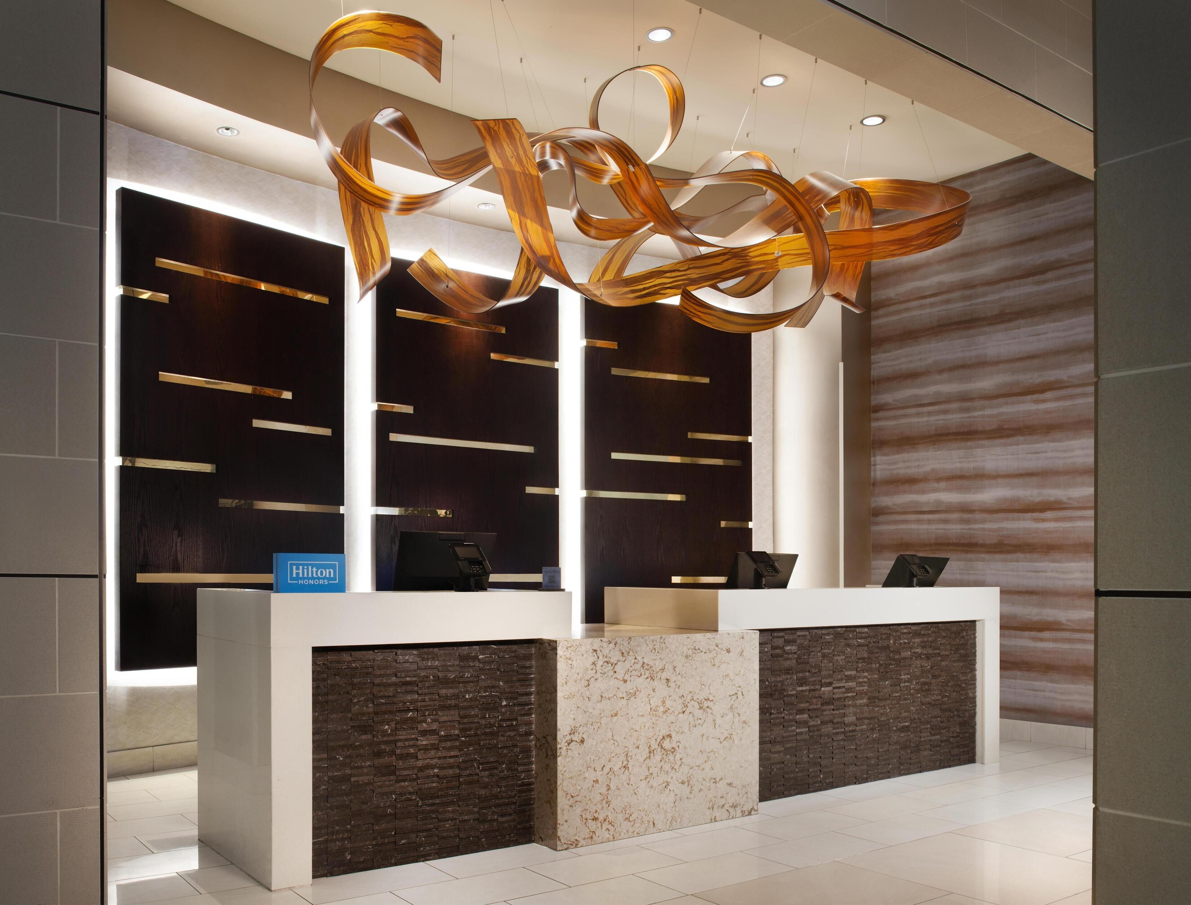 A modern reception desk with a sleek design, featuring a dark wood panel and a marble accent.