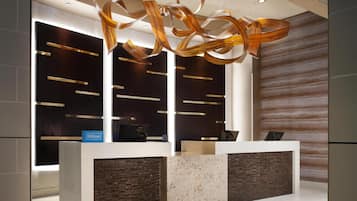 A modern reception desk with a sleek design, featuring a dark wood panel and a marble accent.