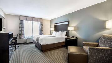 A hotel room with a bed, a desk, a chair, and a small table.