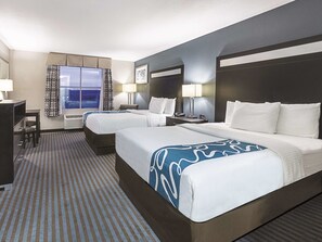 A hotel room with two beds, a desk, and a window with curtains. - La Quinta Inn & Suites by Wyndham Glendive (Glendive)