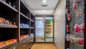 A hotel corridor with storage cabinets, a refrigerator stocked with beverages, and shelves with toiletries. - La Quinta Inn & Suites by Wyndham Glendive (Glendive)