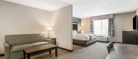 Ein Hotelzimmer mit Sofa, Bett, Schreibtisch und Lampe.