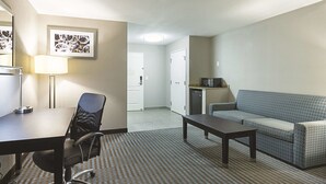 A hotel room with a desk, office chair, sofa, and a microwave. - La Quinta Inn & Suites by Wyndham Glendive (Glendive)