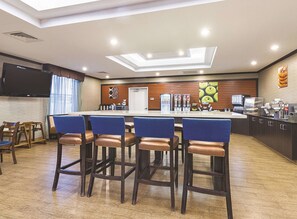 A modern bar area with a long counter, bar stools, and a flat-screen TV mounted on the wall. - La Quinta Inn & Suites by Wyndham Glendive (Glendive)