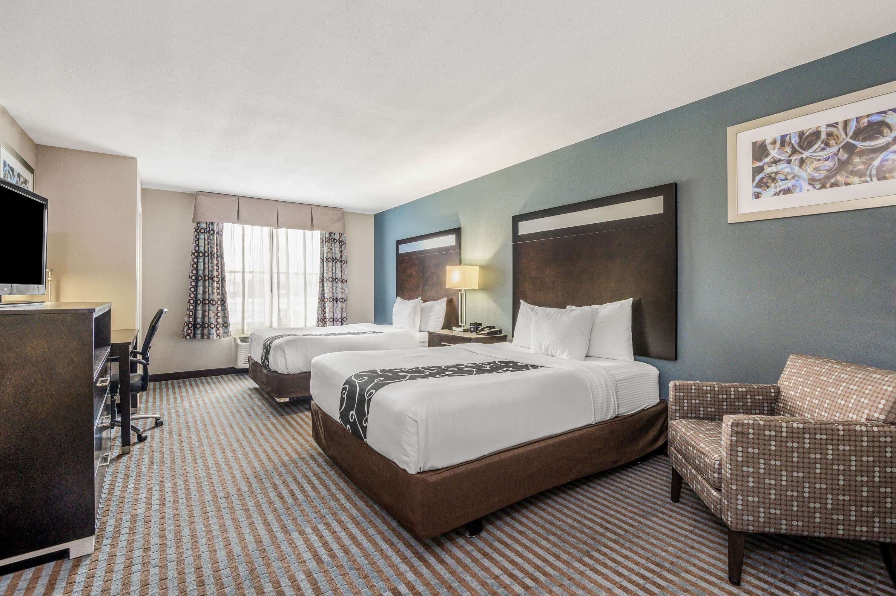 Une chambre d’hôtel avec deux lits, un bureau, une chaise et un téléviseur.