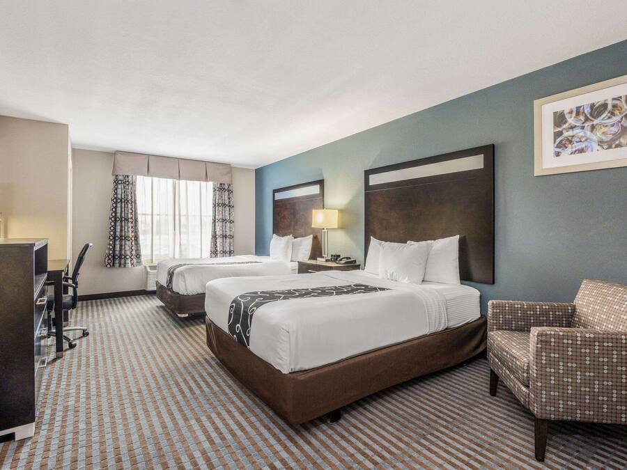 Une chambre d’hôtel avec deux lits, un bureau, une chaise et un téléviseur.