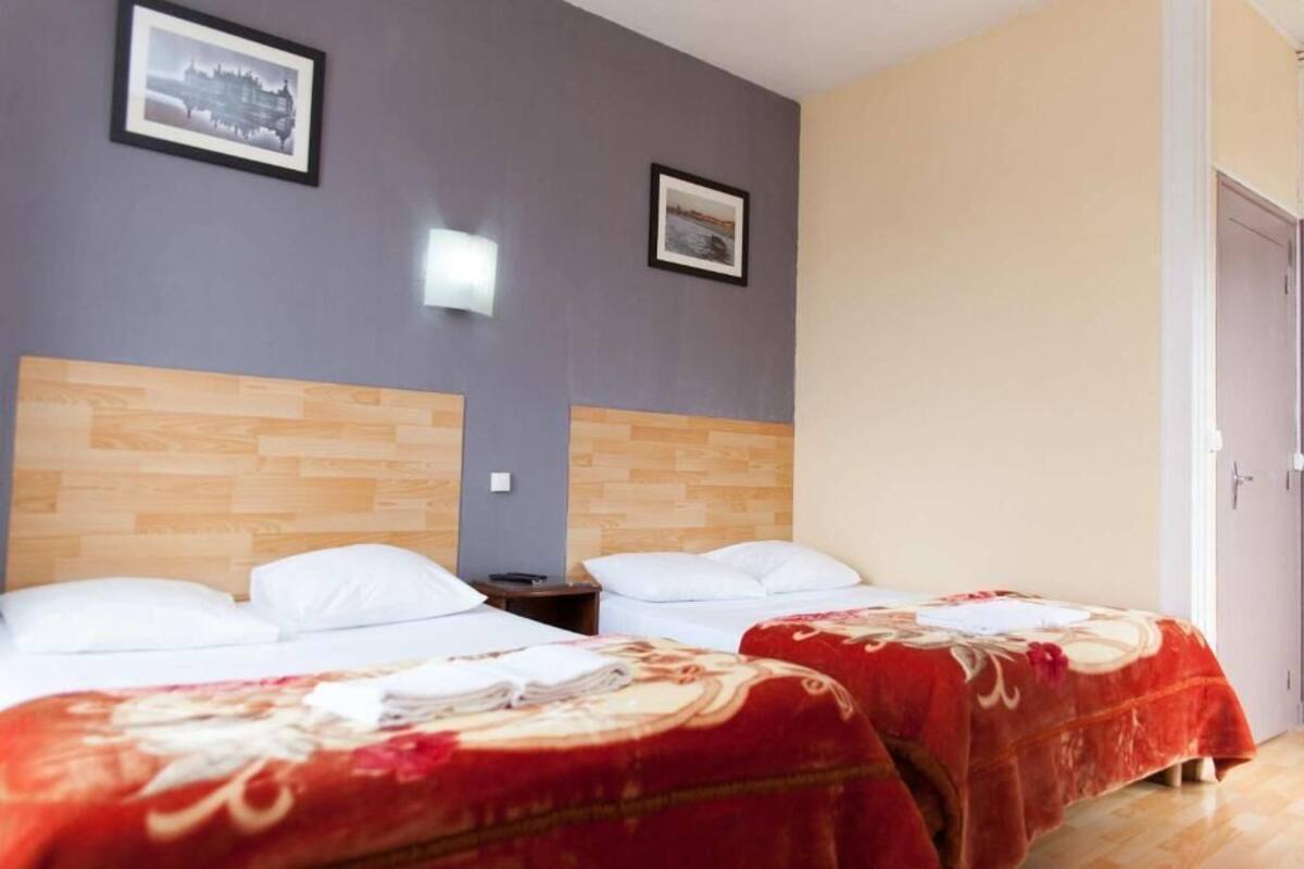 Ein Hotelzimmer mit zwei Betten, Holz-Kopfteilen und einer Tür auf der rechten Seite.