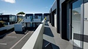 A modern building with a covered walkway, large windows, and a parking area. - Bellano Motel Suites (Christchurch)