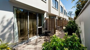 A modern building with large windows and a patio area with outdoor furniture. - Bellano Motel Suites (Christchurch)