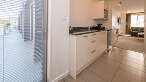 A modern kitchen with white cabinets, a black countertop, and a built-in microwave. - Bellano Motel Suites (Christchurch)