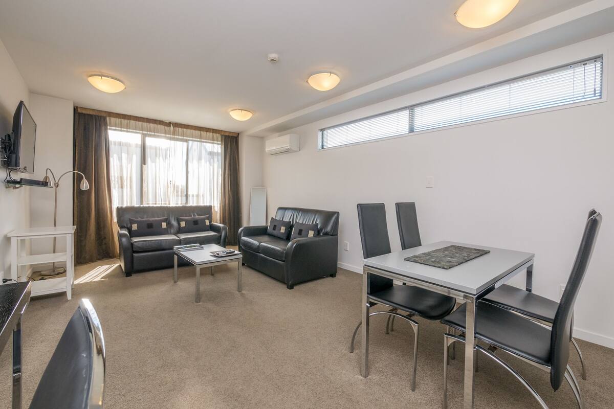 A modern living room with a sofa, a coffee table, and a dining table with chairs.