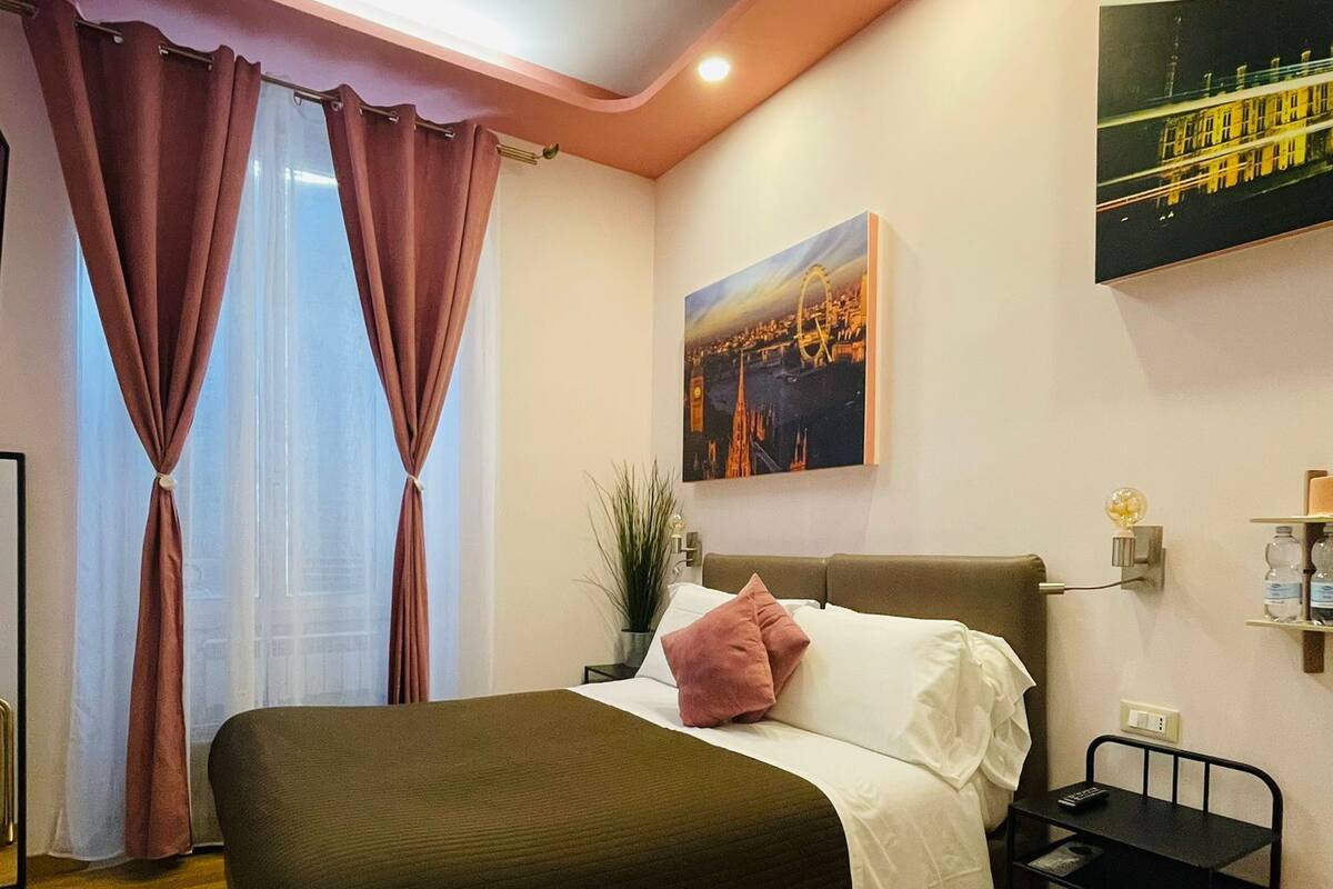 A modern hotel room with a large bed, a nightstand, a wall-mounted TV, and a painting of a cityscape.