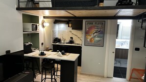 A compact kitchen with a central island, a microwave, and a sink. There's a poster of Pink Floyd on the wall. - City Life Rome (Rome)