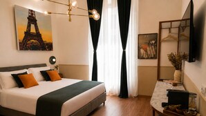 Ein Hotelzimmer mit einem Bett, einem Schreibtisch, einem Spiegel, einem Gemälde des Eiffelturms und einem Fenster mit Vorhängen.