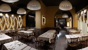 A restaurant with long tables, white tablecloths, and pendant lighting. - City Life Rome (Rome)