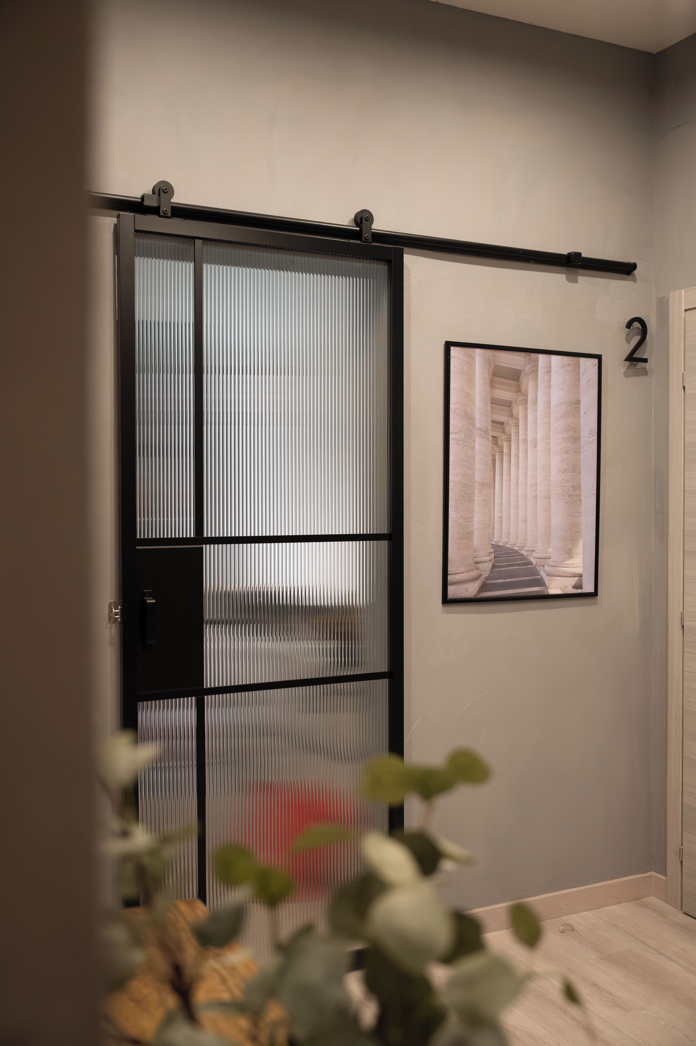 A room with a sliding door, a framed picture on the wall, and a door with a number.
