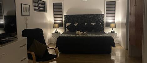 Une chambre à coucher avec un lit, une chaise, un bureau et un téléviseur.