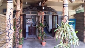 A reception area with a desk, a sign reading "Reception Entrance," and potted plants.