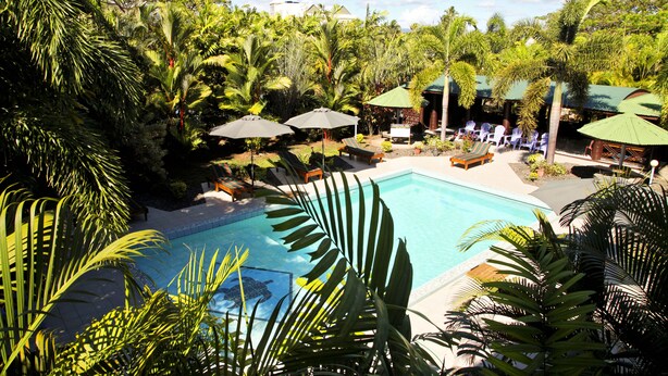 A pool surrounded by lush greenery and shaded seating areas.