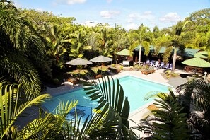 A pool surrounded by lush greenery and shaded seating areas.