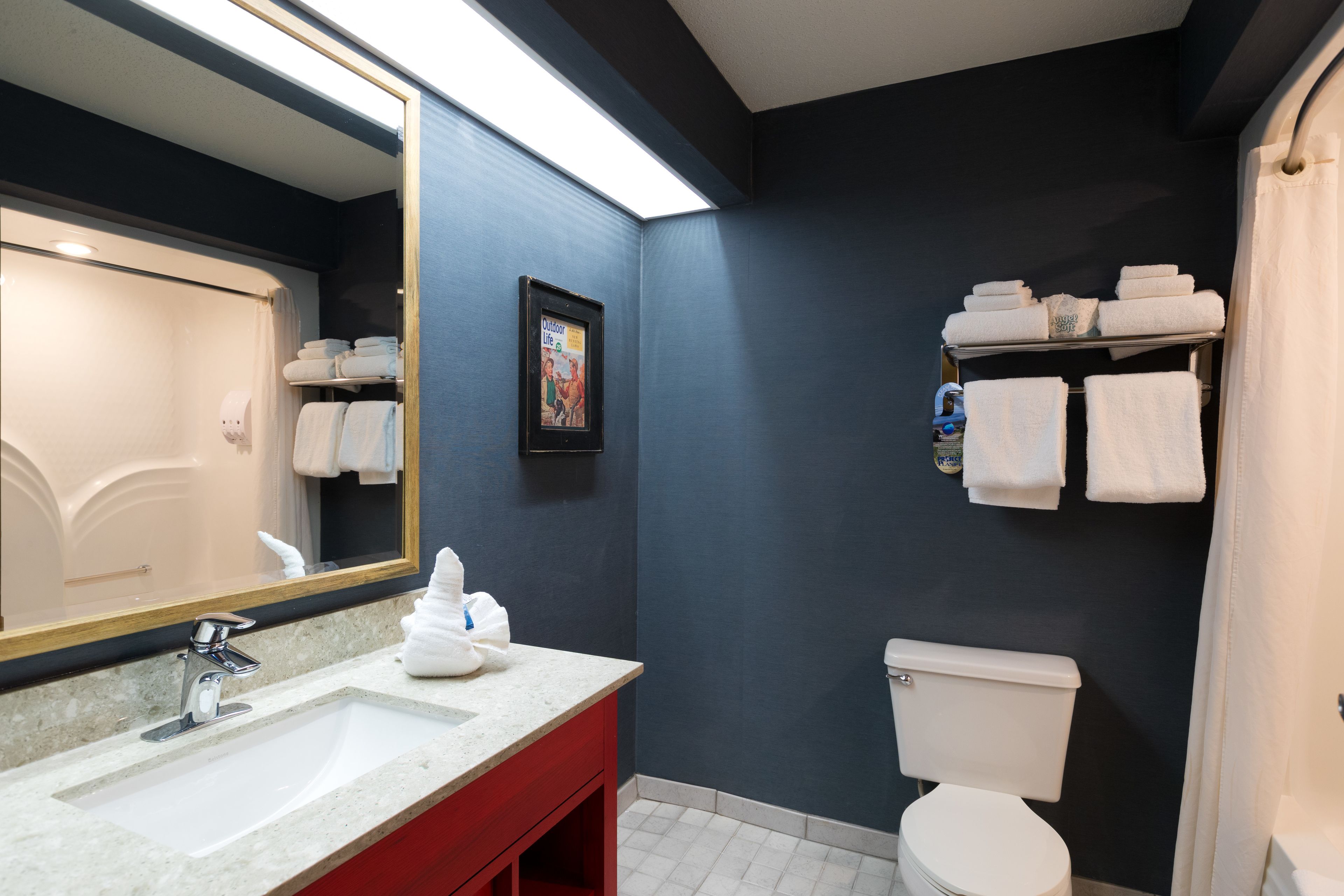 Une salle de bain avec un double lavabo, des toilettes et un porte-serviettes avec des serviettes pliées.