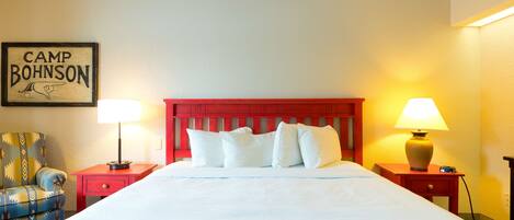 A hotel room with a large bed, two nightstands, a chair, and a wall-mounted sign.
