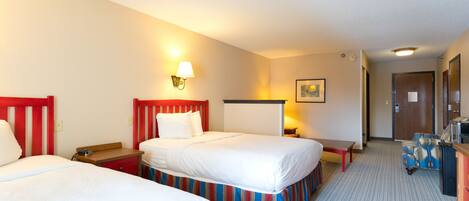 A hotel room with two beds, a desk, a chair, and a small table.