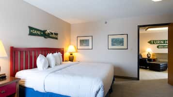 Habitación de hotel con una cama grande, dos mesitas de noche con lámparas, un cabecero rojo y un cartel en la pared que indica indicaciones.