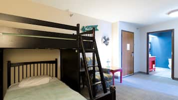 A bunk bed with a ladder, a small desk, a chair, and a door leading to a bathroom.
