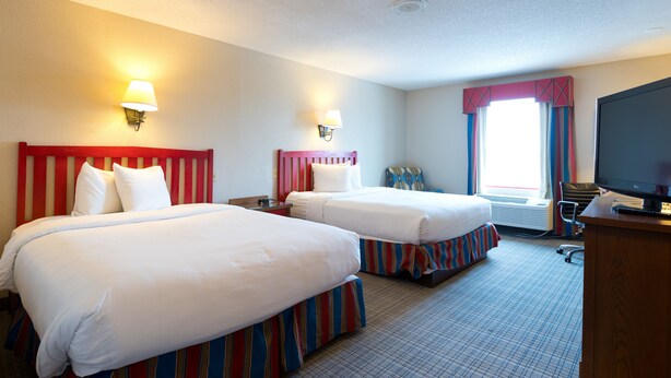 A hotel room with two beds, a desk with a computer, and a television. - Wildwood Lodge (Clive)