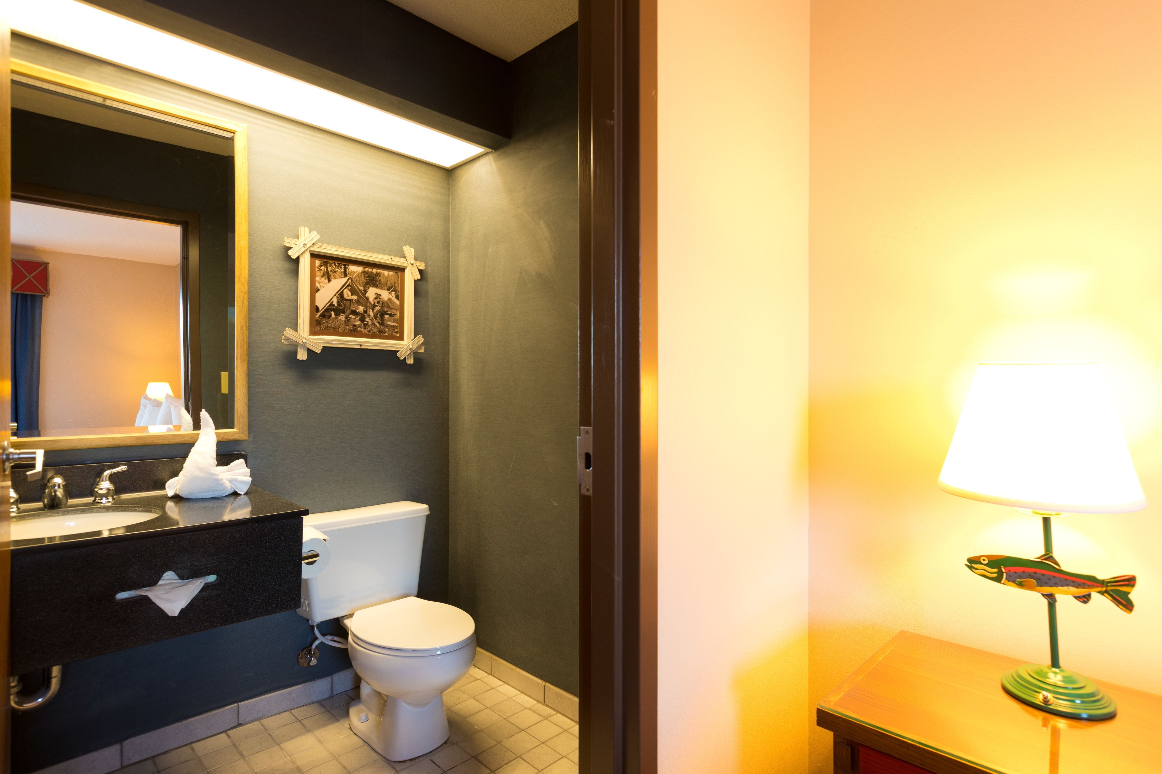 A bathroom with a black vanity, white toilet, and a framed picture on the wall.