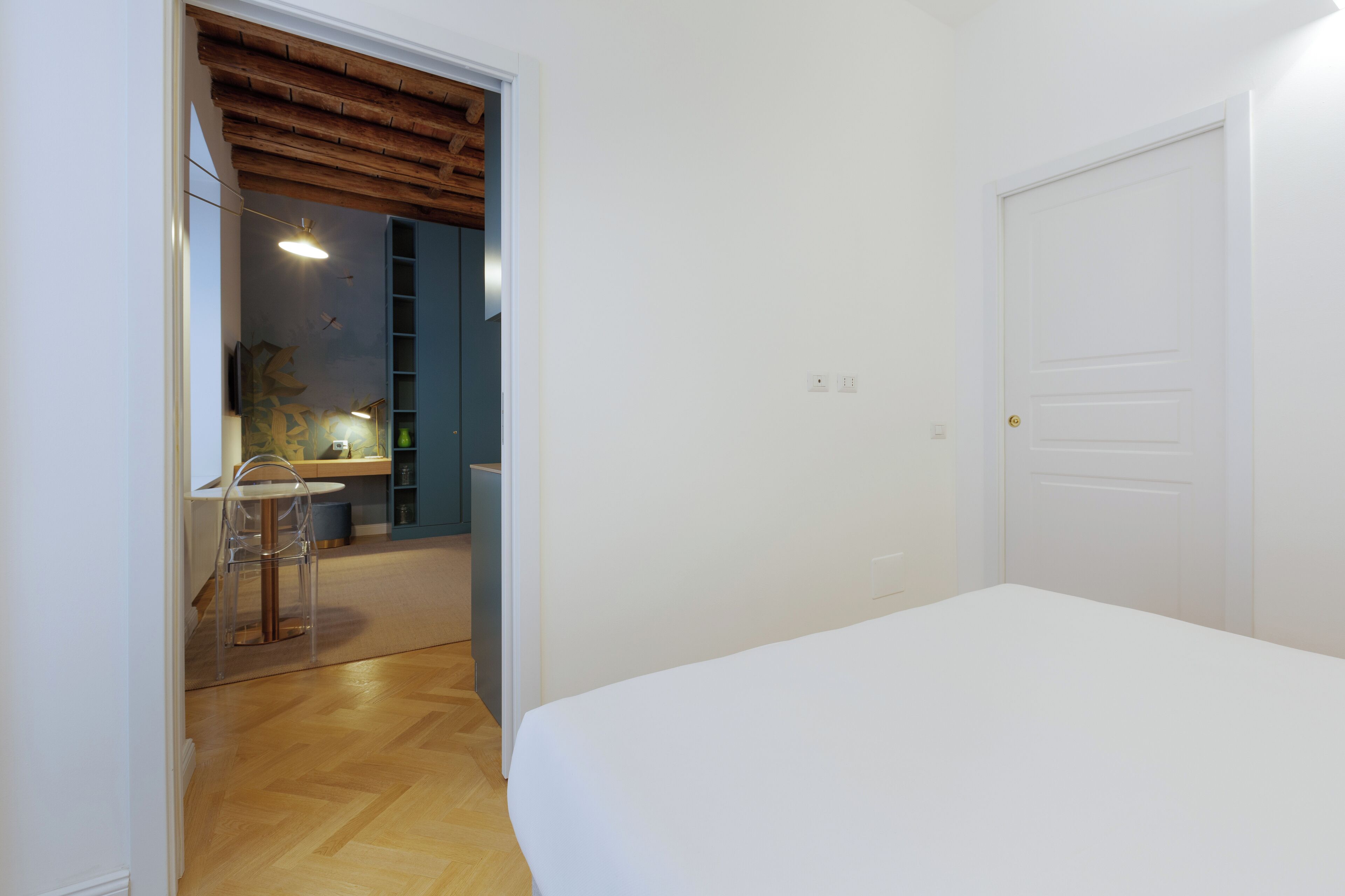 Una camera da letto con pavimento in legno, un letto bianco e una porta.