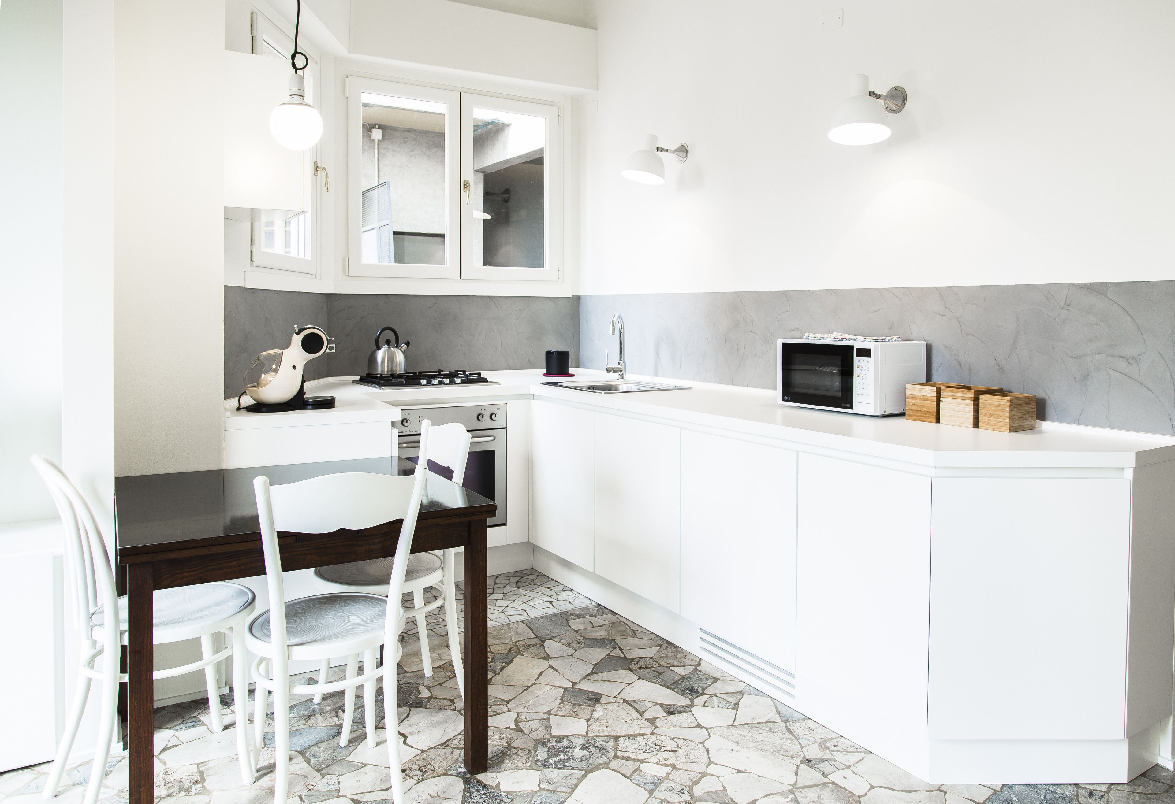 Een moderne keuken met witte kastjes, een eettafel met stoelen, een fornuis en een magnetron.