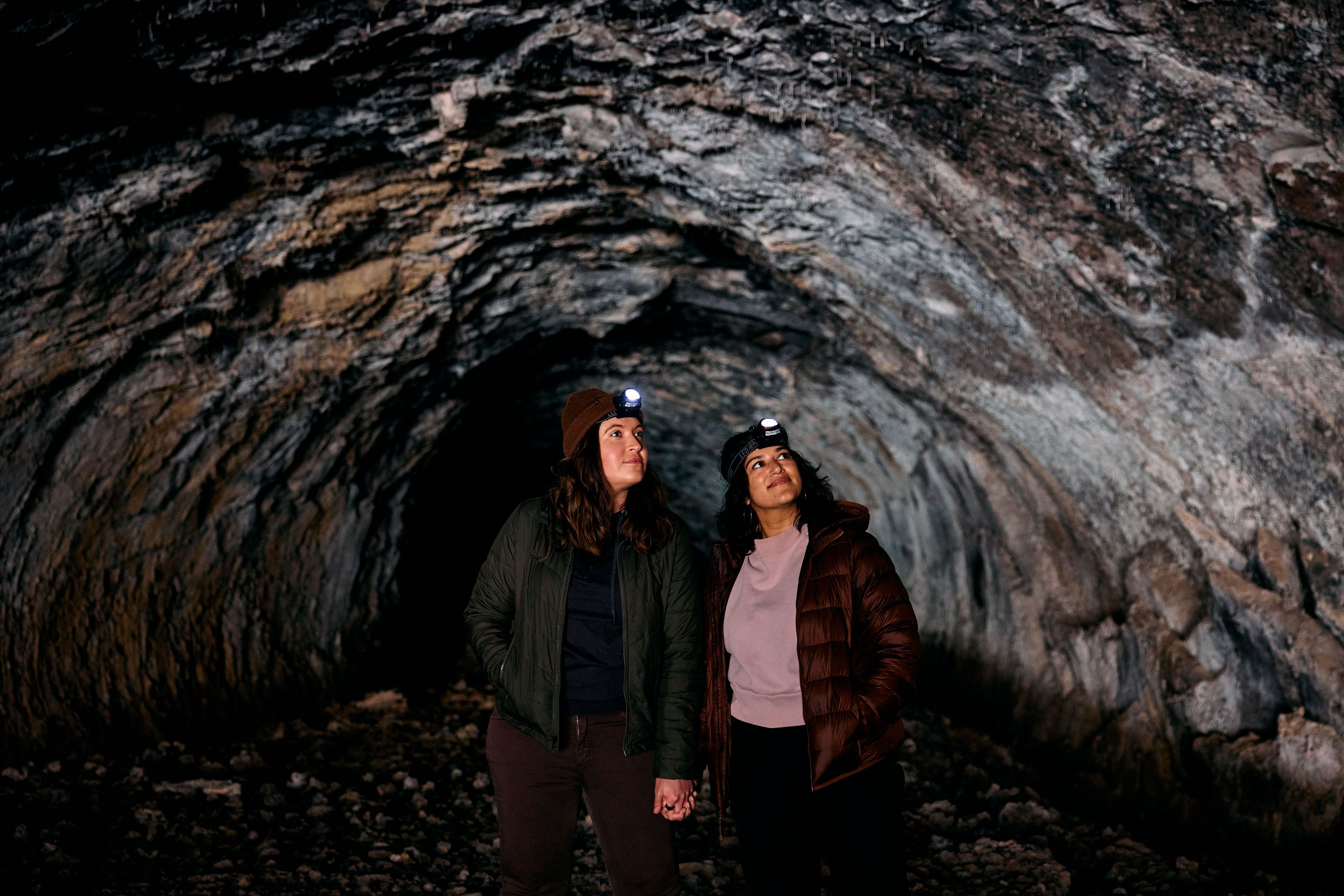 Dos personas de pie en una cueva con paredes rocosas.