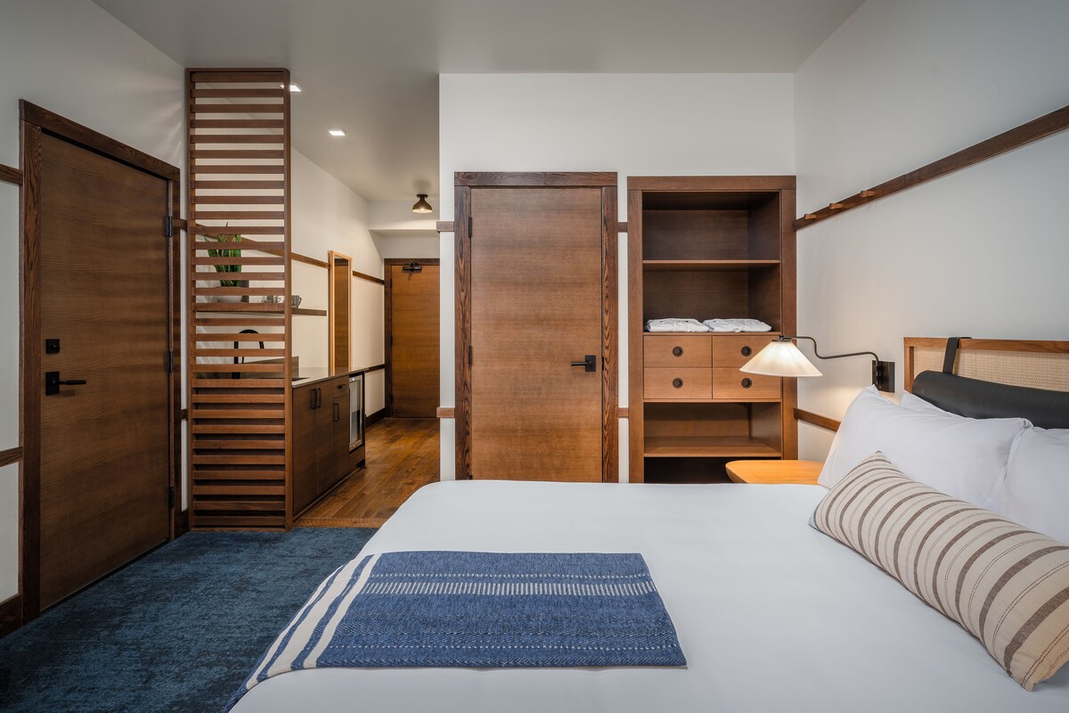 A hotel room with a bed, a desk, a wardrobe, and a staircase.
