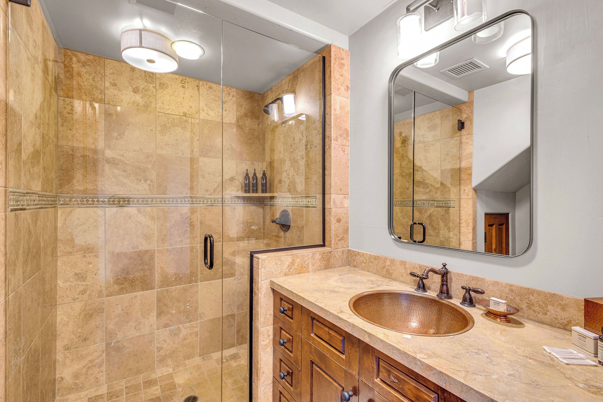 Une salle de bain avec un grand miroir, un lavabo et un espace douche.