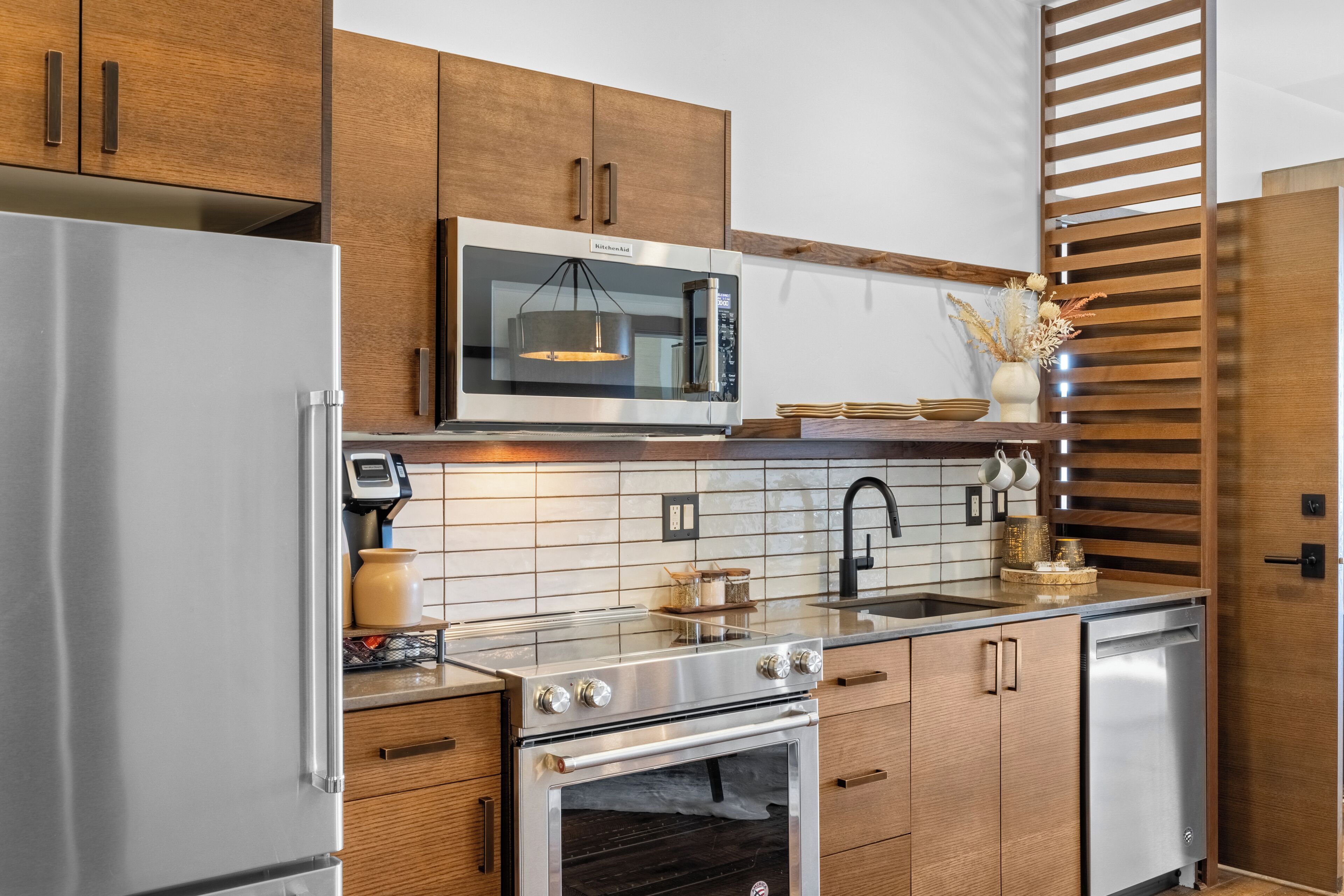 Una cocina moderna con electrodomésticos de acero inoxidable, armarios de madera y salpicadero de azulejos.