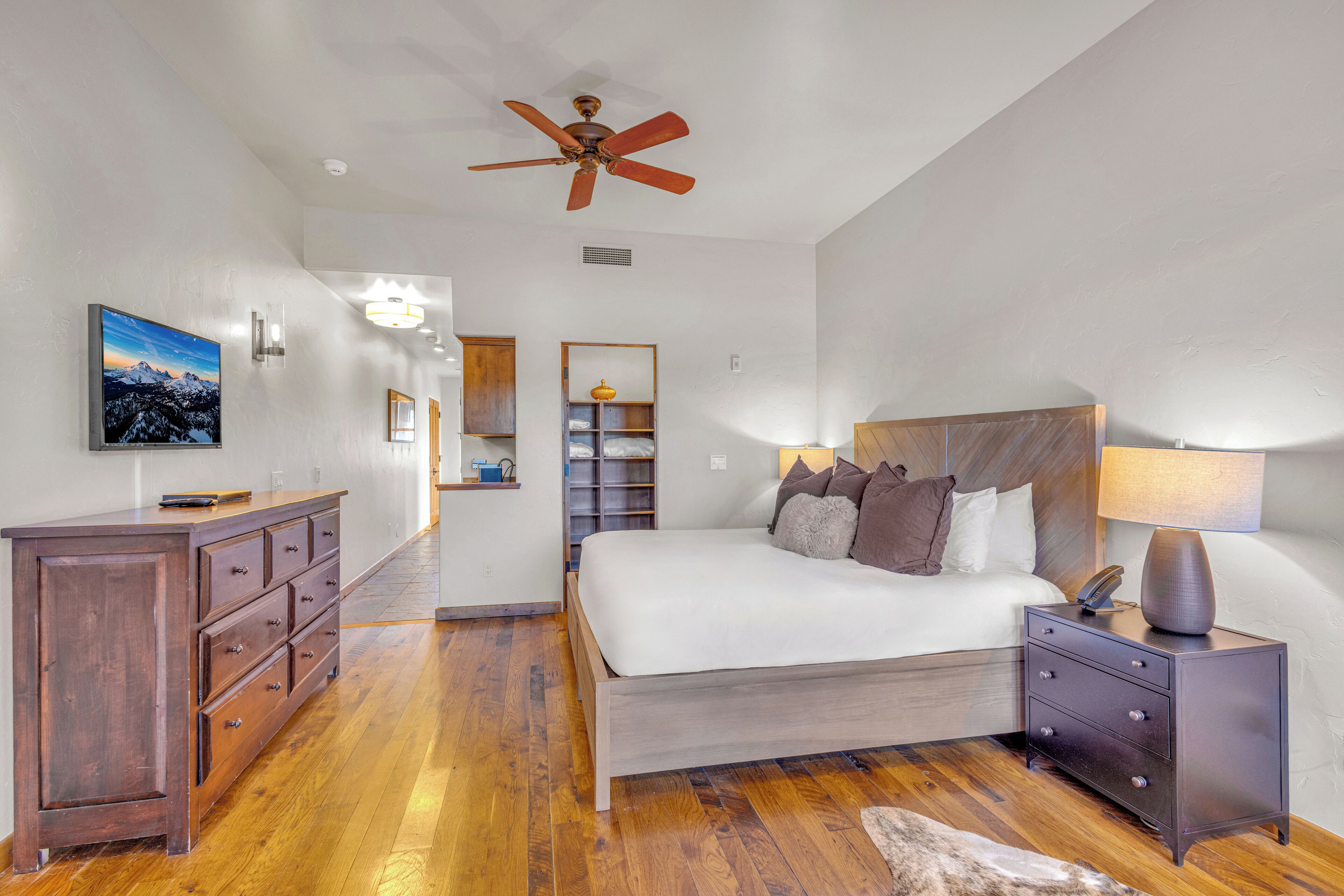 A bedroom with a bed, a nightstand, a dresser, and a ceiling fan.