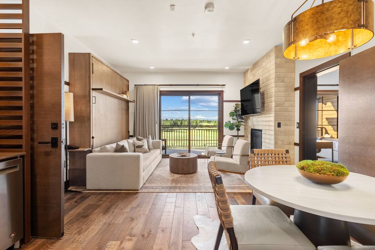 A modern living room with a sofa, chairs, a coffee table, and a dining table.