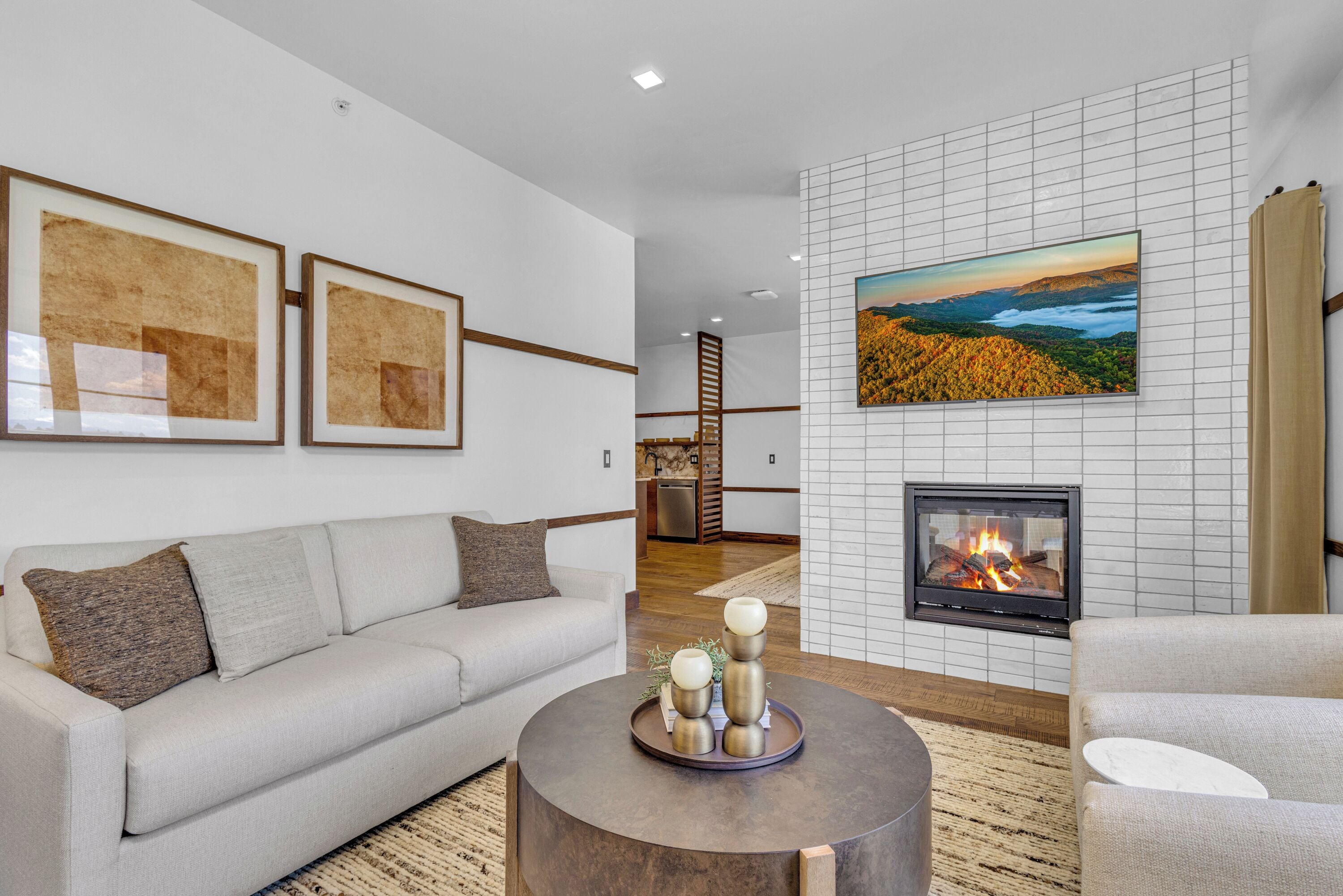 A modern living room with a fireplace, a sofa, a coffee table, and framed artwork on the wall.