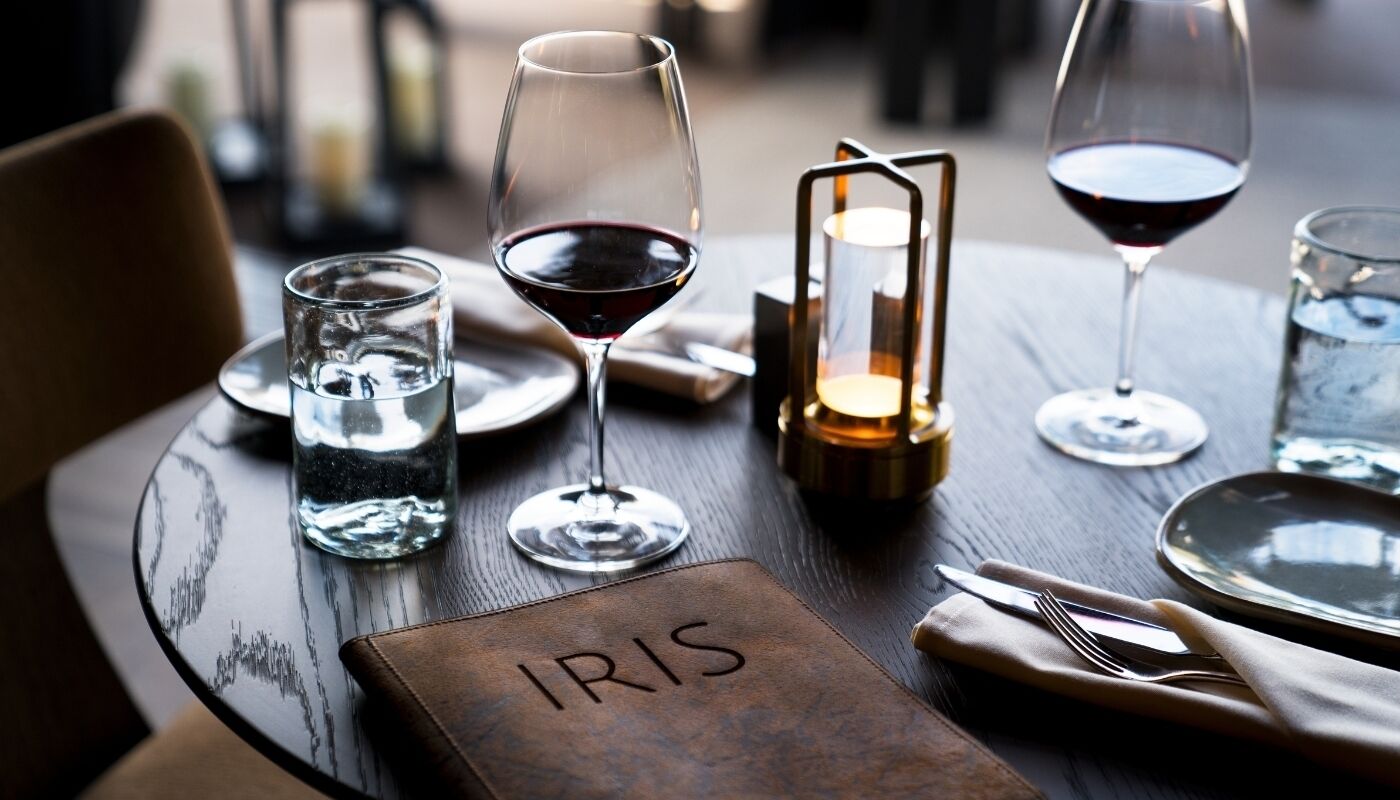 A table set for dining with a candle, glasses, and a menu holder labeled "IRIS".