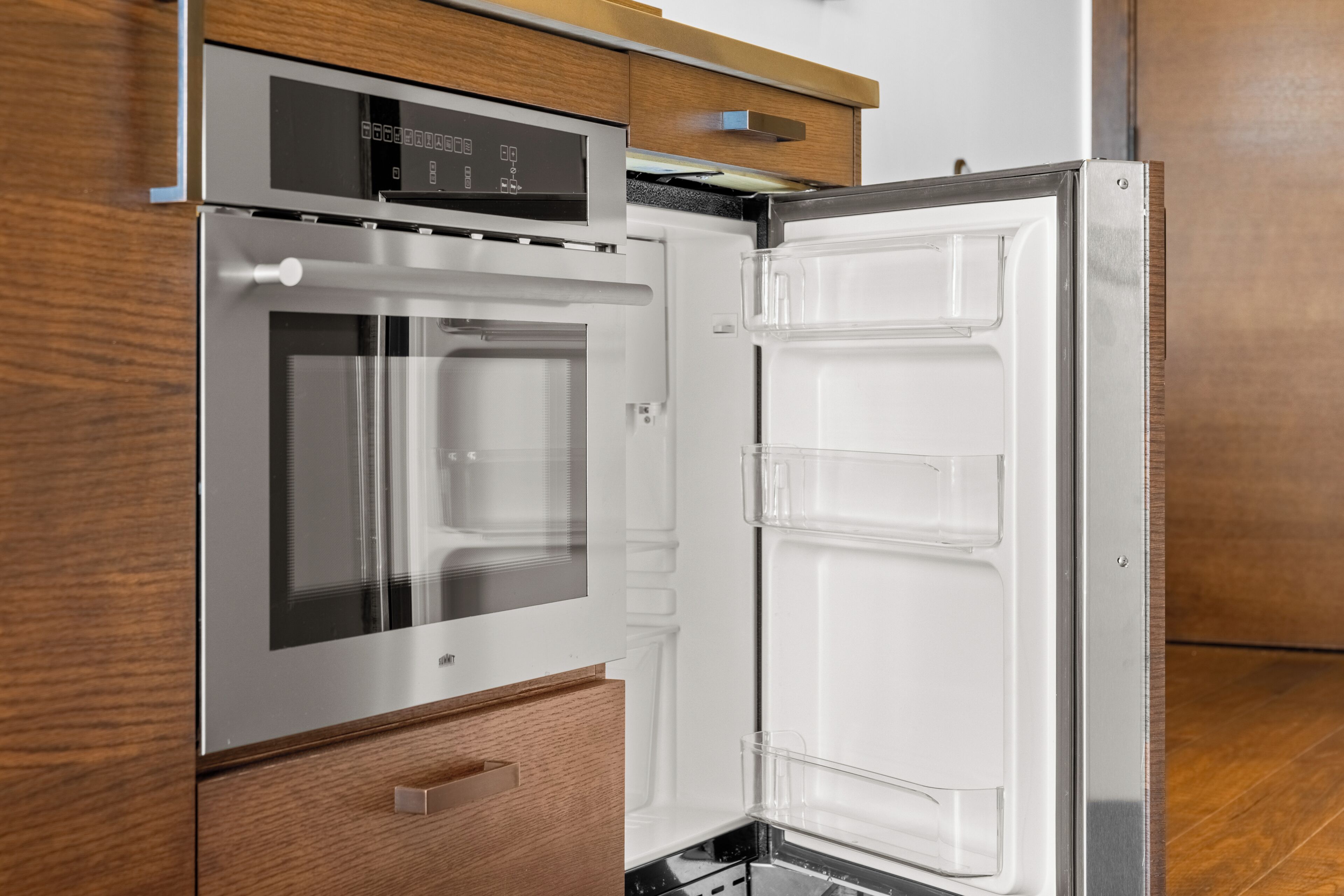 A modern kitchen with a built-in oven and a stainless steel refrigerator.