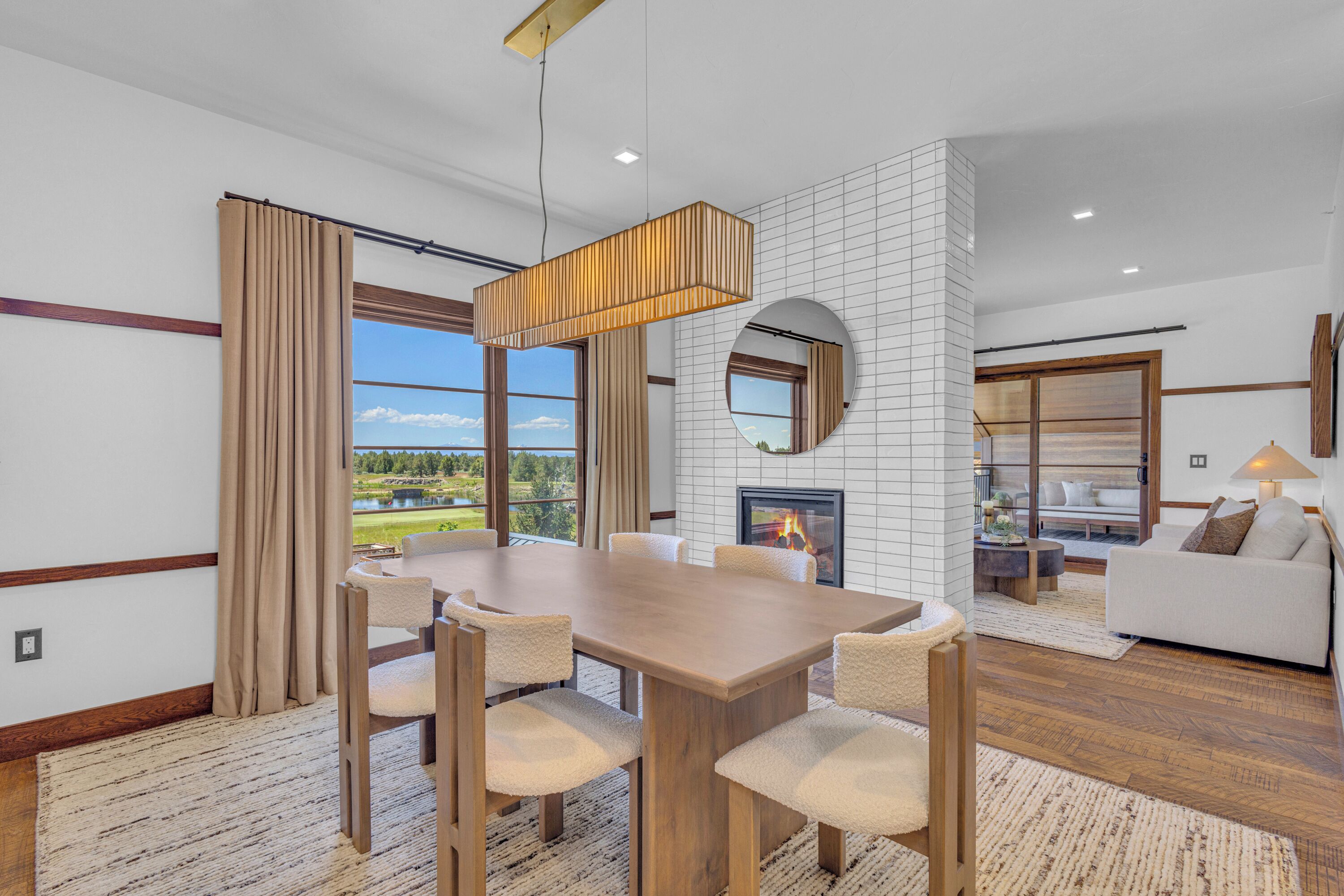 Uma sala de jantar moderna com mesa e cadeiras de madeira, lareira e vista para um campo de golfe.