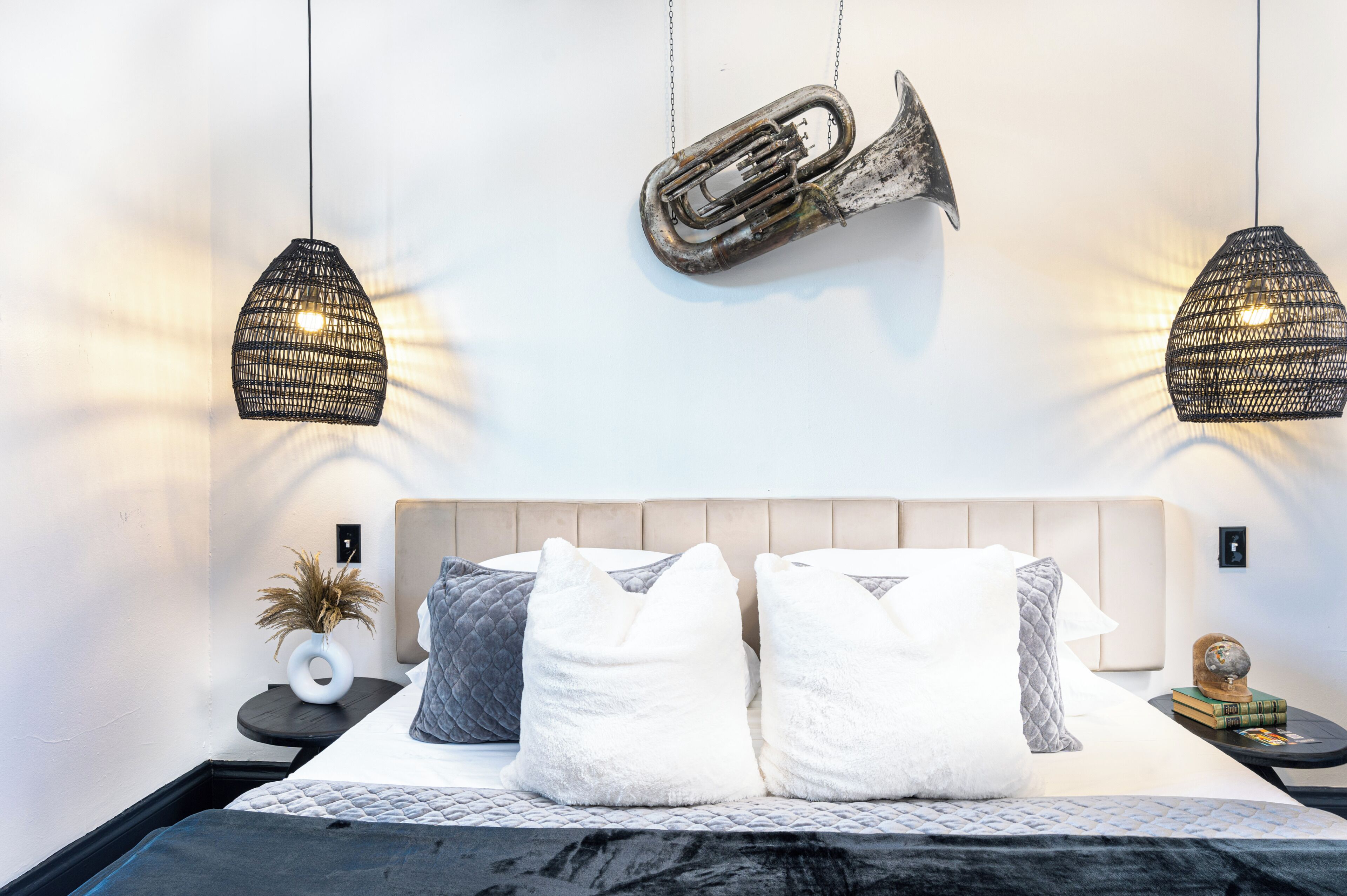 A bedroom with a bed, two wall-mounted lamps, a decorative item, and a small table with a vase.
