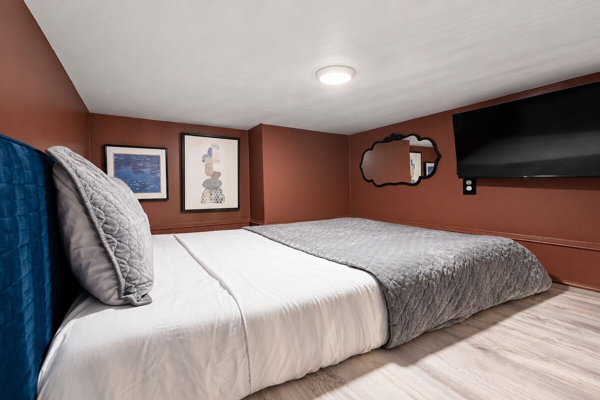 A bedroom with a bed, a TV mounted on the wall, and a framed picture.