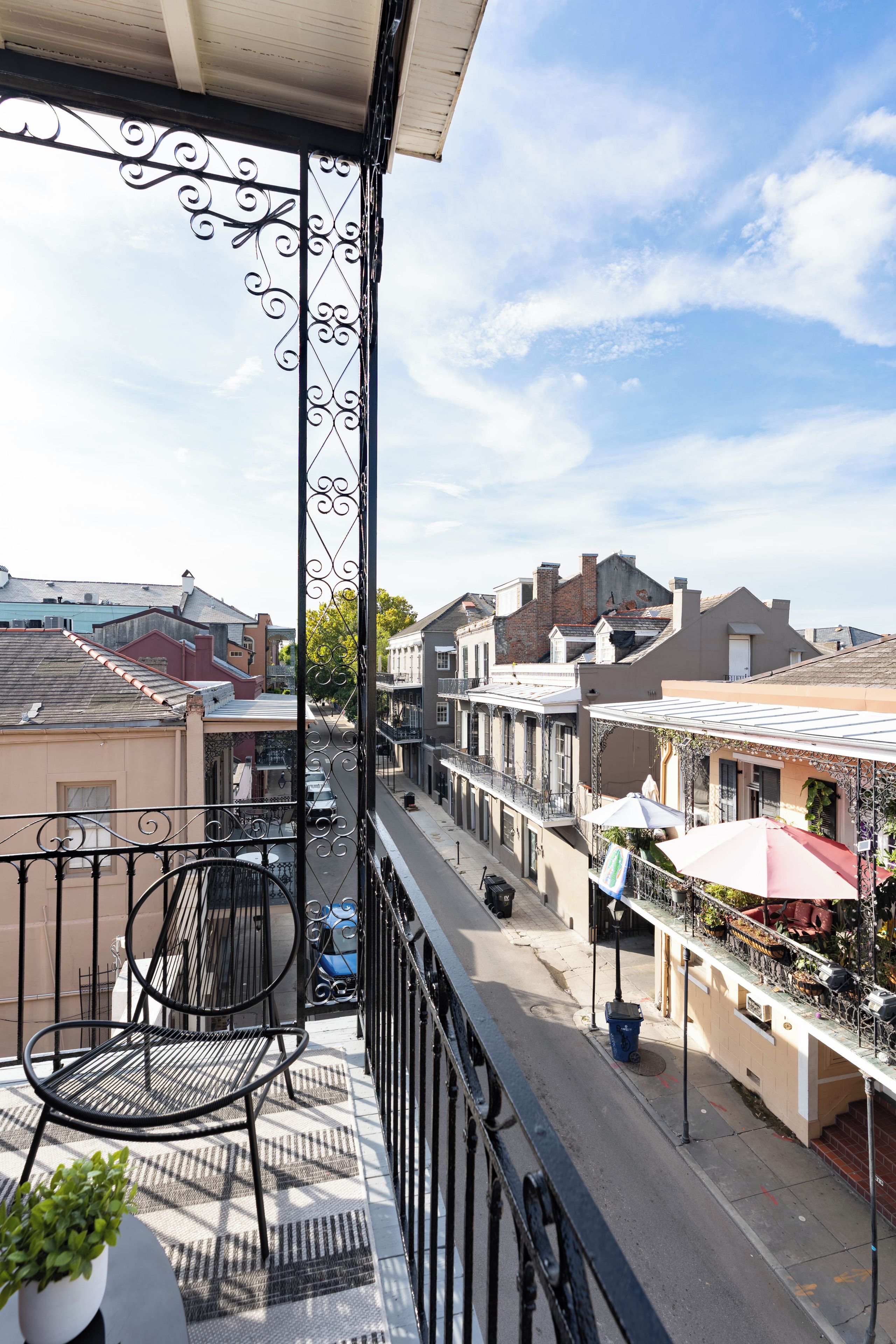 A balcony with a metal railing, a chair, and a potted plant.