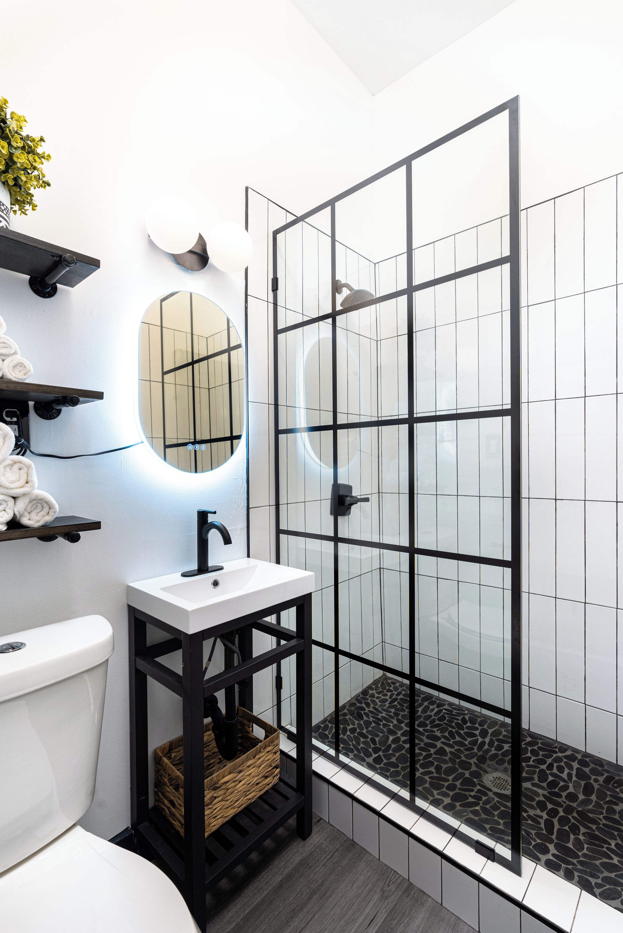 A modern bathroom with a glass shower enclosure, a white sink with a black faucet, and a toilet.