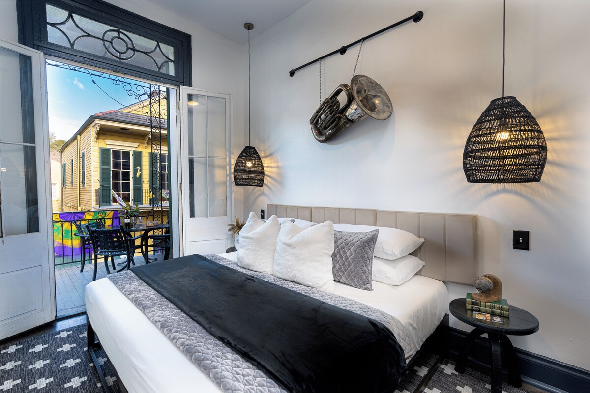 Una habitación de hotel con una cama grande, vistas al exterior y dos lámparas colgantes.