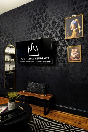 A modern living room with a flat-screen TV, a sofa, a coffee table, and a decorative mirror. - Saint Philip French Quarter (New Orleans)