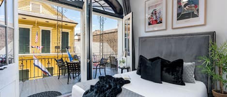 A hotel room with a bed, a balcony with outdoor furniture, and two framed magazine covers on the wall.